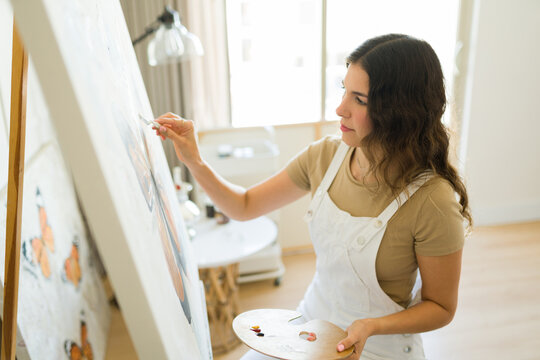 Inspired woman artist holding a brush painting on the canvas