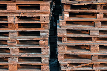 Many Old Used Wooden pallets is stack outdoors in warehouse of cargo delivery enterprise.