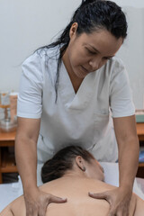 Latin masseuse giving a massage to a blonde girl. Concept: relaxation