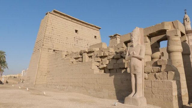 Hand-held shot of the Luxor temple with a large statue outside the walkway
