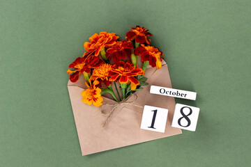 October 18. Bouquet of orange flower in craft envelope and calendar date on green background. Minimal concept Hello fall. Template for your design, greeting card