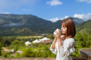 photo of woman life up a cup of coffee,and view of foggy cover over mountain,travel concept
