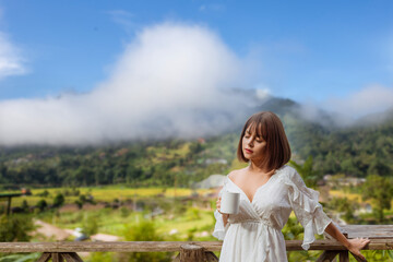 photo of woman life up a cup of coffee,and view of foggy cover over mountain,travel concept