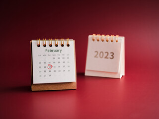 Happy Valentine's day, February 2023 calendar desk on red background. Red circle draws hand mark on day 14 on white table calendar with the February month near white cover with the 2023 year numbers.