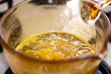Making bubbling caramel syrup on the gas in a golden pot
