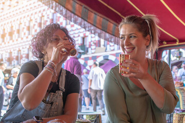Two smiling mature women drinking Moorish tea inside an Arabian Jaimah. Tourist