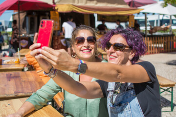 Obraz na płótnie Canvas Girl Friends Taking A Selfie Outdoors. Two Smiling Adult Women Taking A Selfie With A Smartphone. Concept Of Friendship And Happiness