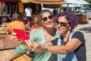 Friends taking a selfie outdoors. Two smiling adult women taking a selfie with smart phone. 