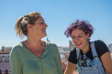 Mature Women Laughing Together In The Street.
Beautiful friends women spending time together having funny conversation in modern city street.