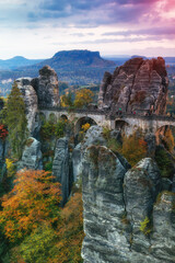 Amazing autumn landscape in Saxon Switzerland National Park. View of The Bastei is a rock formation, exposed sandstone rocks and forest hills at sunset. Germany. Saxony.