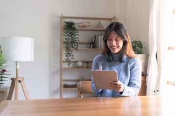 Happy young woman wearing headphone and using digital tablet at home.