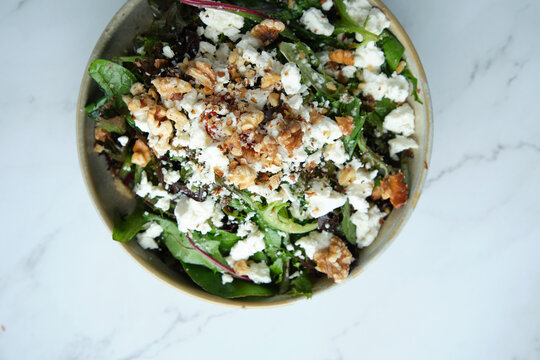 A bowl of green salad with feta and walnuts