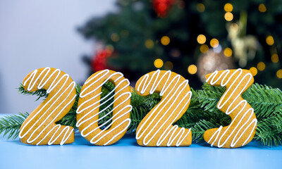 2023 Cookie number made of gingerbread cookie with white icing with Christmas tree and Christmas lights on blue background. Merry Christmas and Happy New Year.