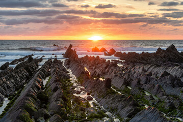 Beautiful sunset landscape image of Welcome Mouth Beach in Devon England with beautiful rock formations