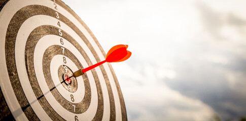 Close up shot red darts arrows in the target  of dartboard center on dark blue sky background....