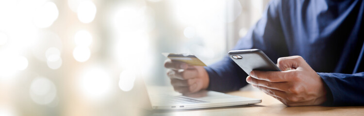 Man holding credit card and using smartphone at home online shopping ecommerce internet banking spend money work from home concept.