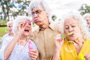 Group of senior friends bonding at the park - Elderly old people meeting and having fun outdoors - obrazy, fototapety, plakaty