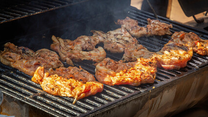 Chicken pieces are cooked on the grill of a street fast food restaurant.