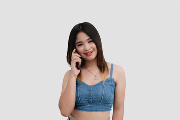 A smiling Asian girl calls her parents using her mobile phone while smiling for a studio shot isolated on white background.