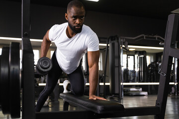 Naklejka premium Fit and muscular african man trains with dumbbells.