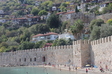 Obraz premium ALANYA, Turkey - October 2022: Alanya city beach near the fortress wall. Urban development on a mountain slope. October 2022. Turkey.