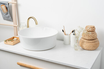 Fototapeta na wymiar Bathroom marble counter with sink, candles and toothbrushes near white wall, copy space
