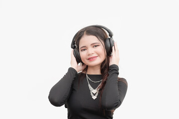 A studio shot of a young woman listening to music using her wireless headphones.