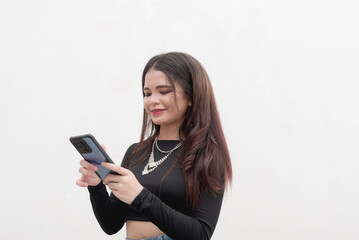 A smiling young woman chats with her boyfriend via online messaging using her cellphone. Studio shot isolated on a white background.