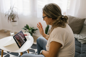 Adult woman having video call at home using tablet