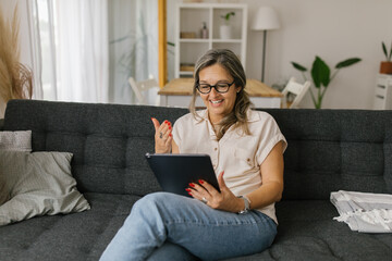 Adult woman having video call at home using tablet