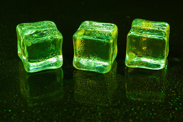 Green ice cubes on black background.