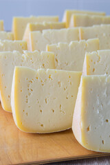 Cheese pieces on a wooden board, selective focus. Goat cheese, long ripening craft cheese.