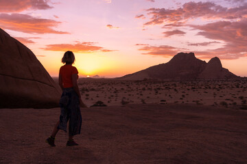 A woman walking towards the sunset in the Namibian desert