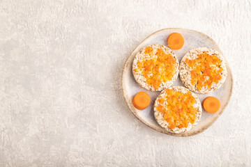 Carrot jam with puffed rice cakes on gray concrete. Top view, copy space.