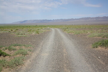 The lonely road in the Gobi Desert, Umnugovi, Mongolia. It is sandy and dusty. During the long winter months, the road is covered with the snow.