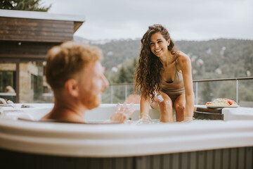 Young couple enjoying in outdoor hot tub on vacation