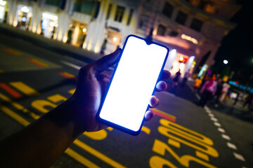 holding a smart phone with white screen on street at night 