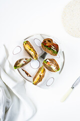 Photo of a delicious freshly made sandwiches from brown bread with meat, red fish, greens, sauce, eggs, cheese and other sandwich ingredients on a white modern porcelain plate on a white background  