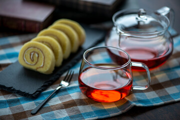 ガラス製のカップに入った紅茶とスレートプレートに乗ったロールケーキ
