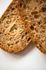 Photo of a fresh homemade delicious brown bread lying on a whit modern flat porcelain plate on a white background