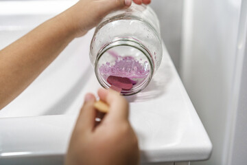 Chemical experiment on growing crystals. Child hands take out grown crystal from a jar.