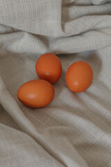 Three eggs lying on a beige, neutral background