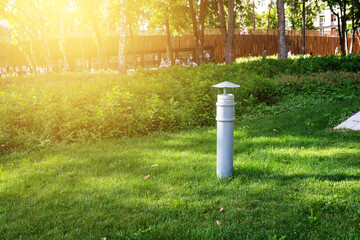Park infrastructure. A ventilation pipe sticks out of a green lawn in a multi-level park