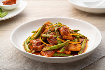 Stir fried sliced pork and red curry paste with sting bean in white plate,pad prik gaeng