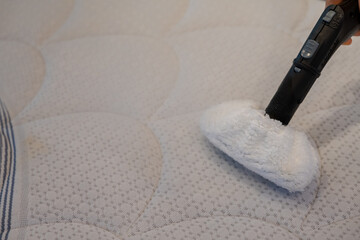 Someone cleaning a bed with Steam Cleaner.Home cleaning concept.