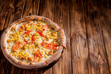 Pizza for children on a cream base with chicken fillet, tomatoes, corn and mozzarella cheese on wood background. Copy space.