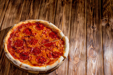 Pizza with tomato sauce, mozzarella, salami, chili, honey on wood background. View from above, copy space