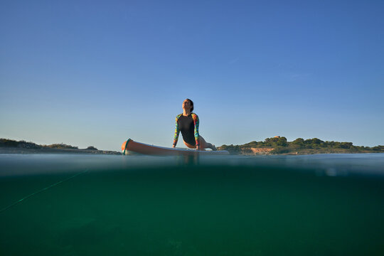 Woman Practicing Yoga On Paddleboard In Cobra Pose