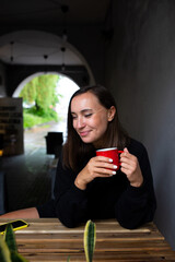  Young woman alone drinking a drink in a terrace cafe on a rainy day