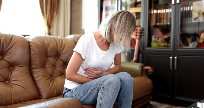 Sick young woman in pain and holding stomach